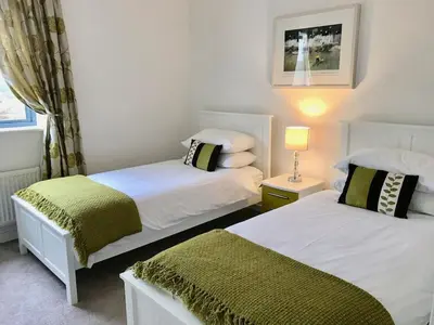 a bedroom with two beds and a lamp and a window at The Waterwheel Apartment, Charlestown in Charlestown