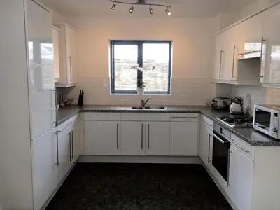 a kitchen with white cabinets and a sink and a window at The Waterwheel Apartment, Charlestown in Charlestown