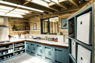 a kitchen with blue cabinets and wooden walls at Glamping at Macdonald's Farm in Saint Ervan