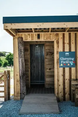 a wooden building with a sign that reads changing practices at Glamping at Macdonald's Farm in Saint Ervan