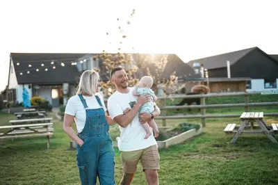 a man and woman holding a baby in a field at Glamping at Macdonald's Farm in Saint Ervan