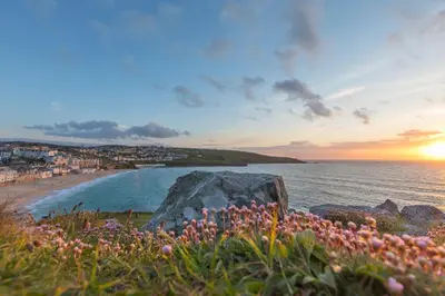 a beach at sunset with a large rock and flowers at Island Studio with on-site parking in St Ives