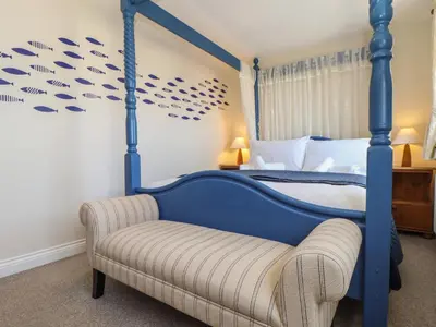 a bedroom with a blue canopy bed and a chair at Kingsholm in Truro