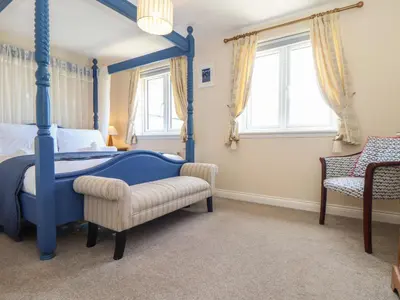 a bedroom with a blue canopy bed and a chair at Kingsholm in Truro