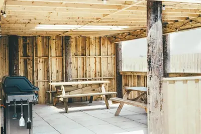 a picnic table and benches in a room with wooden walls at The Potting Barn in Saint Ervan