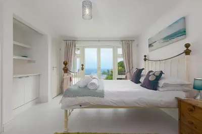 a bedroom with a bed with a view of the ocean at Moonbeams in St Ives