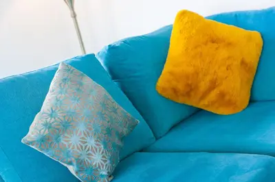a blue couch with a yellow pillow on it at Moonbeams in St Ives