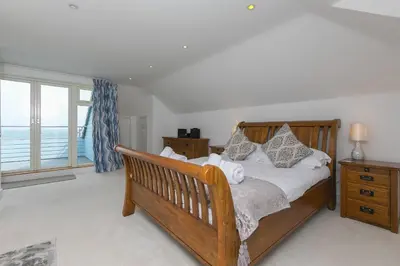 a bedroom with a wooden bed with a view of the ocean at Moonbeams in St Ives