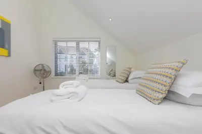 a bedroom with a white bed with a fan and a window at Bay View in St Ives