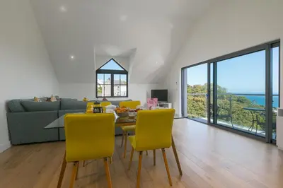 a living room with a table and yellow chairs at Bay View in St Ives