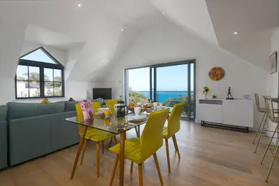 a living room with a table and yellow chairs at Bay View in St Ives