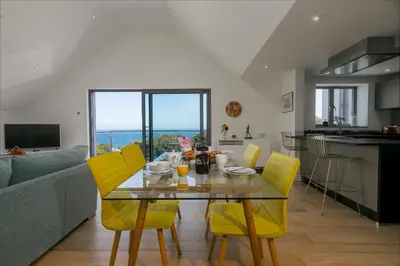 a dining room and kitchen with a table and yellow chairs at Bay View in St Ives