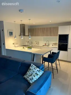 a living room with a blue couch and a kitchen at Beachside Apartment in Newquay