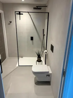 a white bathroom with a toilet and a shower at Beachside Apartment in Newquay