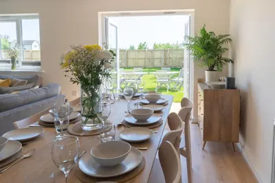 a dining room with a table with plates and glasses at The Bright House, St Eval - near Padstow, Mawgan Porth, Watergate, Bedruthan & Porthcothan in Saint Ervan
