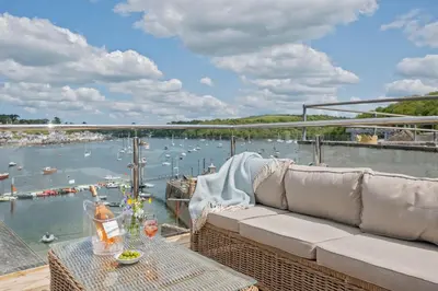 a couch on a balcony with a view of a harbor at Enchanting Harbourside Cottage with Panoramic Views in Polruan