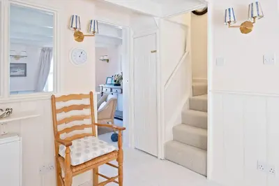 a hallway with a wooden chair and a staircase at Enchanting Harbourside Cottage with Panoramic Views in Polruan