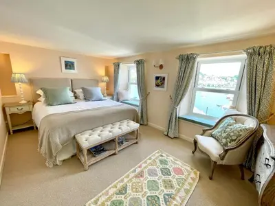 a bedroom with a bed and a chair and a window at Enchanting Harbourside Cottage with Panoramic Views in Polruan