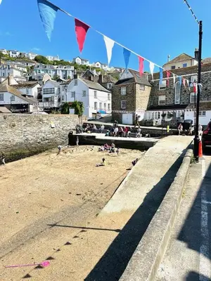 a beach with flags and people sitting on the sand at Enchanting Harbourside Cottage with Panoramic Views in Polruan