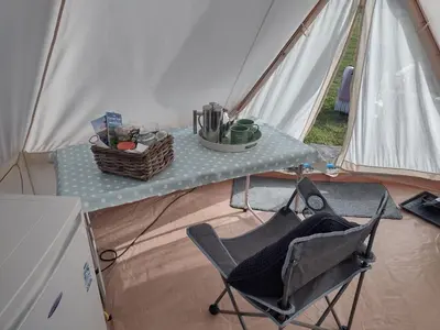 a tent with a table and a chair in it at Hawk's View Bell Tent at Higher Hawksland Farm in Saint Issey