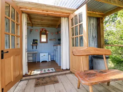 a wooden porch with a door and a chair at Shepherds Retreat in Launceston