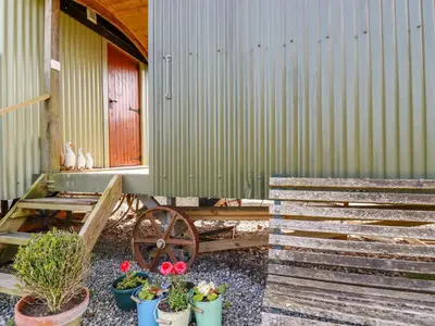a building with potted plants in front of a house at Puddle Duck Shepherds Hut in Launceston