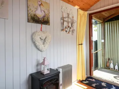 a room with a heater and a heart hanging on the wall at Puddle Duck Shepherds Hut in Launceston