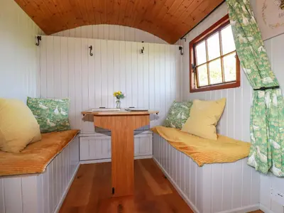 a room with two benches and a table in a tiny house at Puddle Duck Shepherds Hut in Launceston