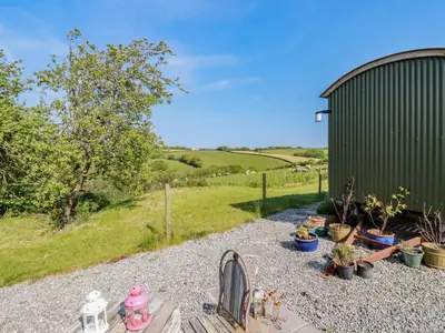 a garden with potted plants and a green building at Puddle Duck Shepherds Hut in Launceston