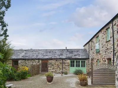 an exterior view of a stone building with a green door at The Coach House - 24439 in Bodmin