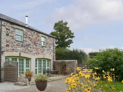 a brick house with yellow flowers in front of it at The Coach House - 24439 in Bodmin