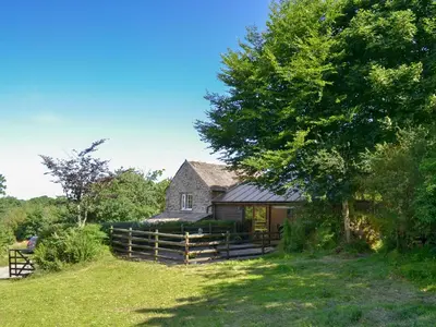 a house with a fence and a tree at Wallhouse Barn in Blisland