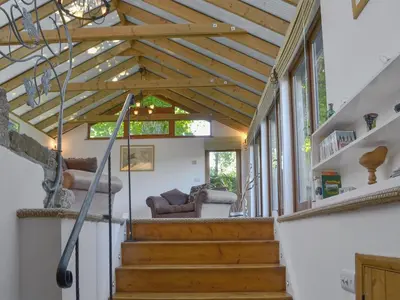a living room with a wooden ceiling and stairs at Wallhouse Barn in Blisland