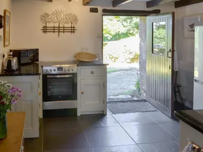 a kitchen with a stove and an open door at Wallhouse Barn in Blisland