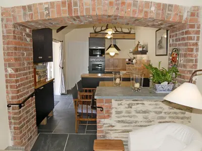 a kitchen and living room with a brick wall at Game Larder Cottage in Saint Mabyn