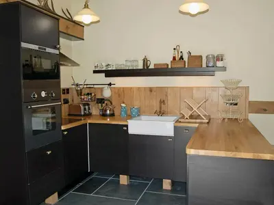 a kitchen with black cabinets and a white sink at Game Larder Cottage in Saint Mabyn