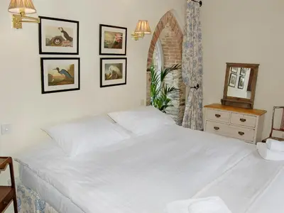 a bedroom with a white bed and a mirror at Game Larder Cottage in Saint Mabyn