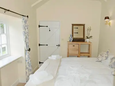 a bedroom with a white bed and a mirror at Game Larder Cottage in Saint Mabyn