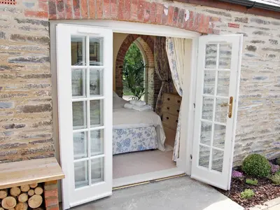 an open door to a bedroom with a bed at Game Larder Cottage in Saint Mabyn
