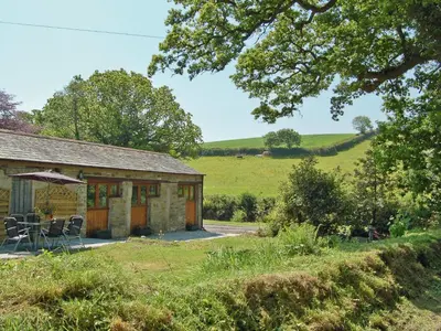 a cottage with a table and chairs in front of it at The Stables in Bodmin