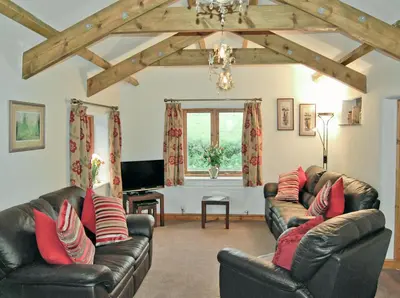 a living room with two leather couches and a television at The Stables in Bodmin