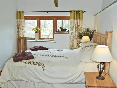 a bedroom with a bed with a white comforter at The Stables in Bodmin