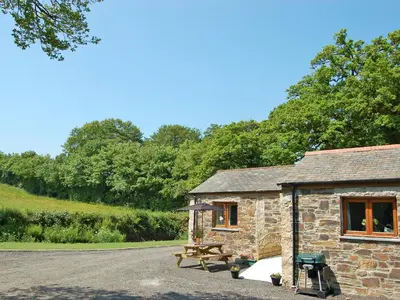 a stone cabin with a picnic table and a bench at The Stables in Bodmin