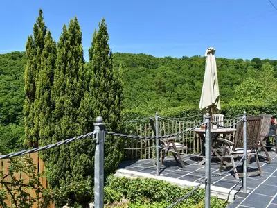 a patio with an umbrella and chairs and trees at The Old Chapel in Washaway