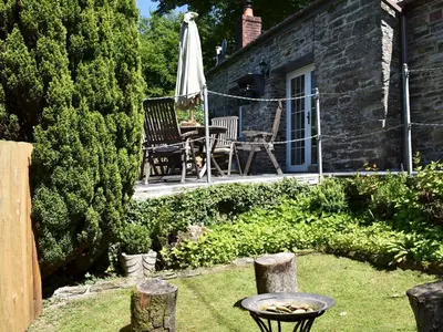 a patio with a table and a chair and an umbrella at The Old Chapel in Washaway