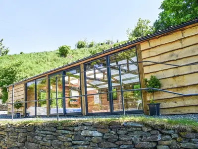 a glass house with a stone wall at The Old Chapel in Washaway