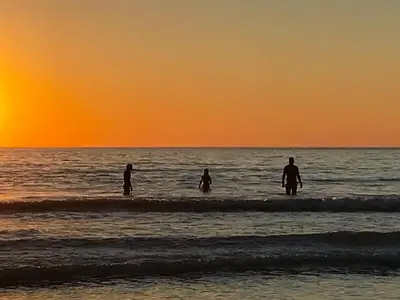 a group of people standing in the ocean at sunset at Cross Cottage in Saint Breward
