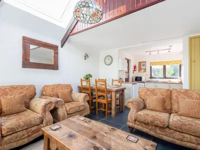 a living room with two couches and a table at Cross Cottage in Saint Breward