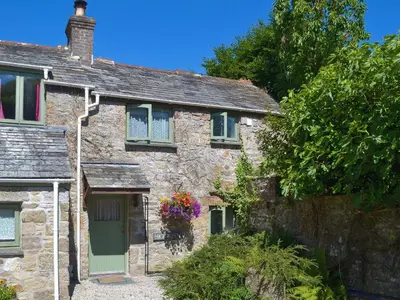 an old stone house with a green door and flowers at High View in Saint Breward