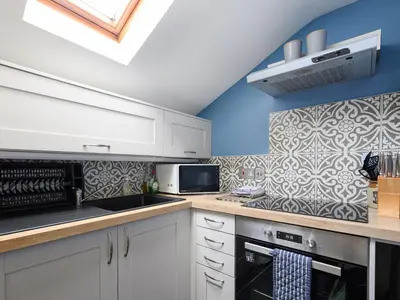 a kitchen with white cabinets and a blue wall at High View in Saint Breward